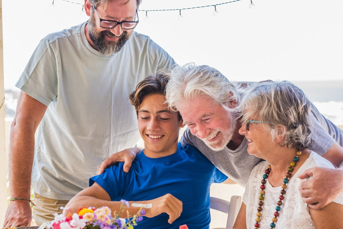 Intergenerational family of four laughing around the dining table.