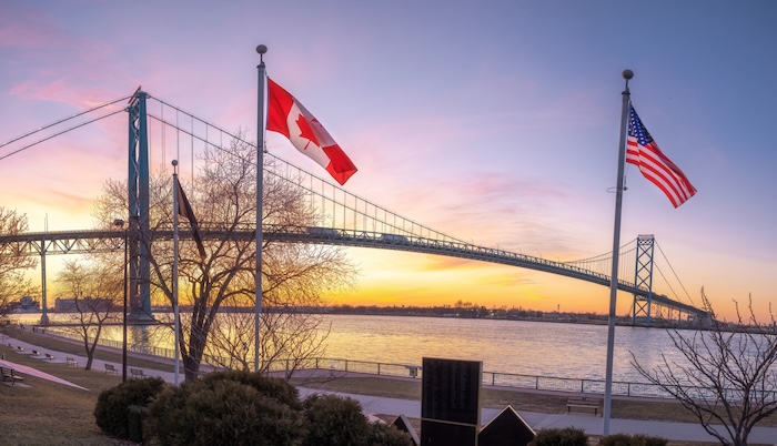 Michigan bridge at sunset with both the Canadian and US flags flying.