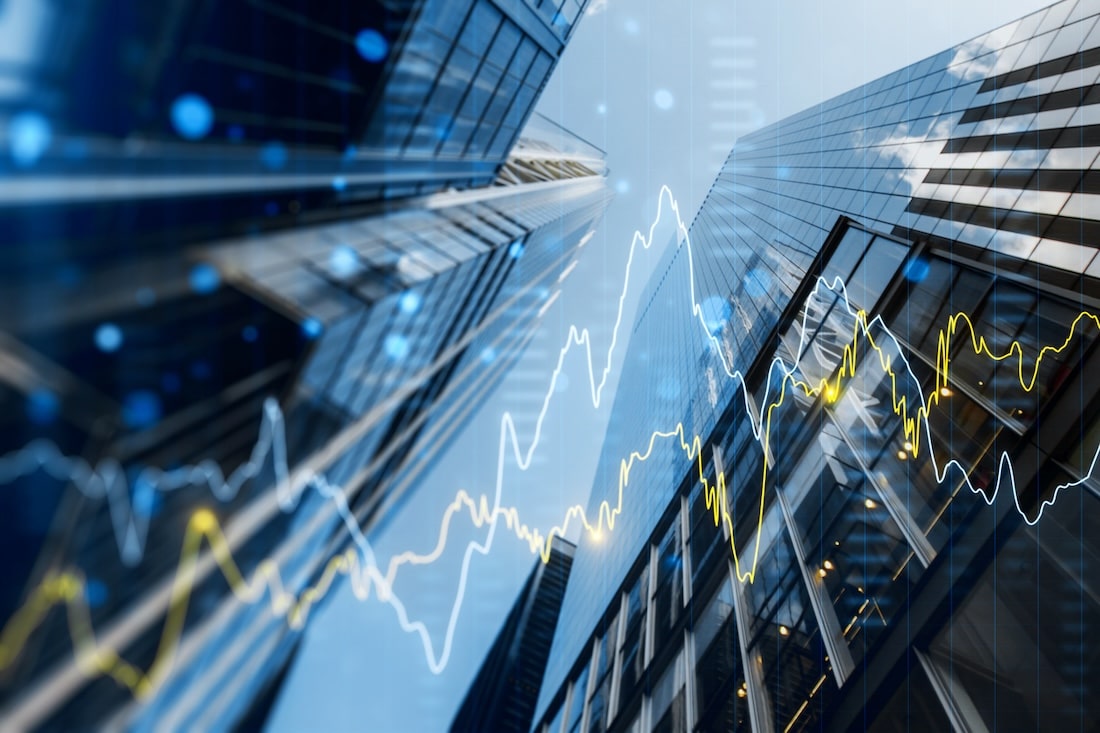 A double exposure image of skyscrapers with overlay of financial graphs, set against a blurred background.