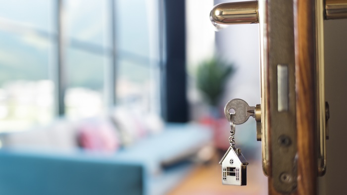 House keys hanging from the lock on the open door of an apartment.