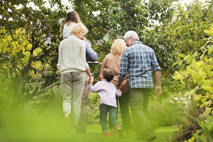 Multi-generational family with grandparents, kids, and grandkids walking through a park.