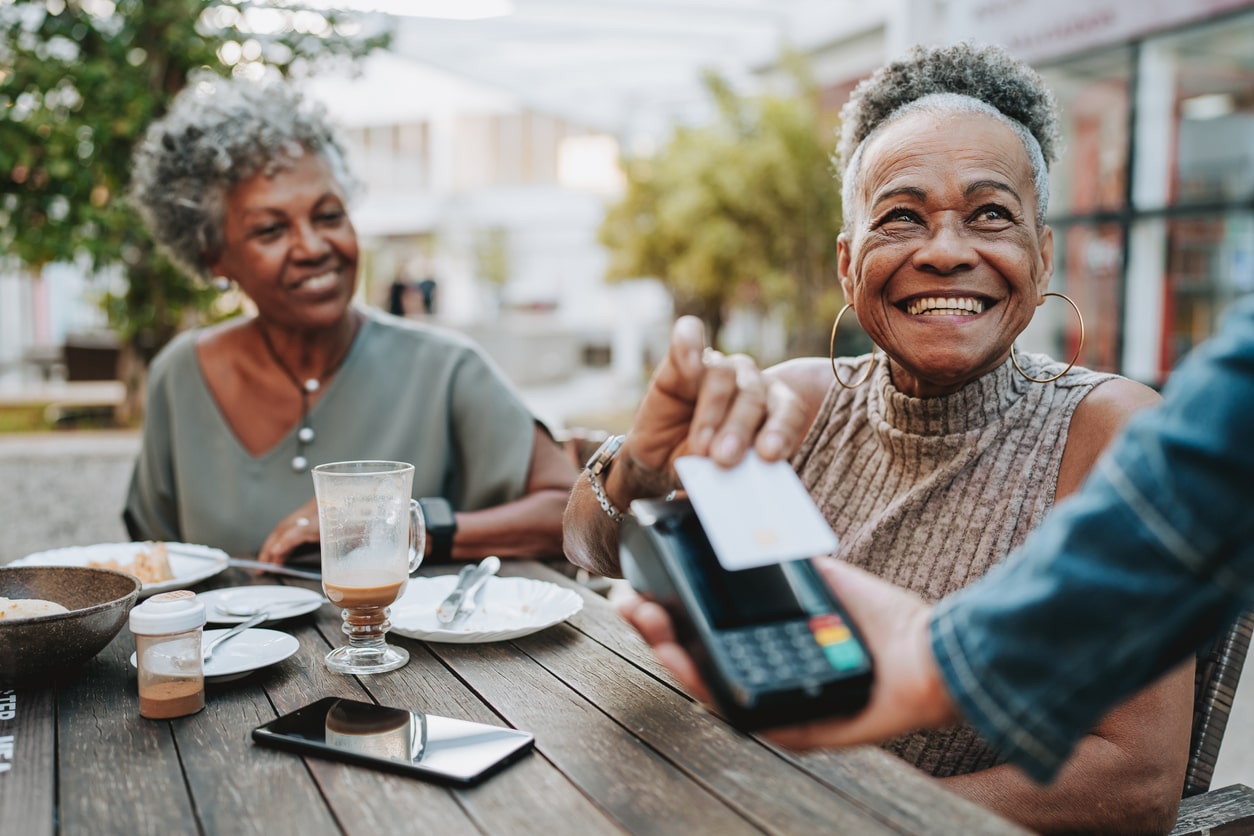 senior best girl friends at lunch with one of them paying with a credit card